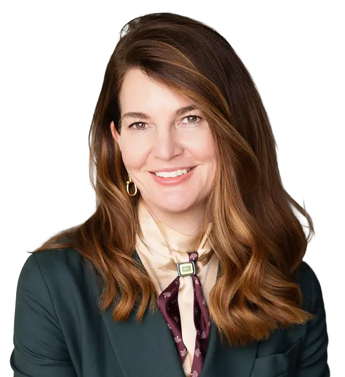 Professional headshot of a smiling woman with wavy brown hair, wearing a dark blazer and cream blouse.